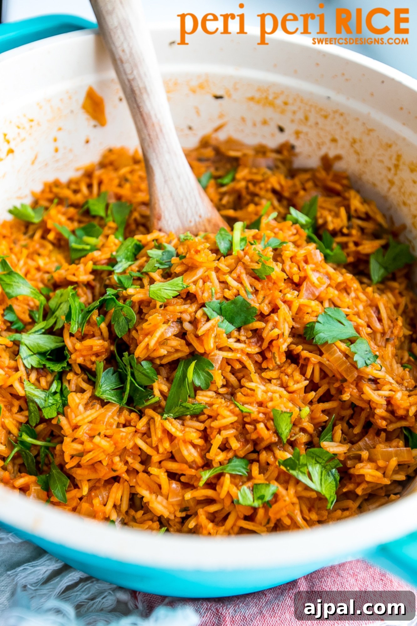 A close-up shot of fluffy, spicy peri peri rice served in a blue bowl with a wooden spoon, showcasing its rich color and texture.