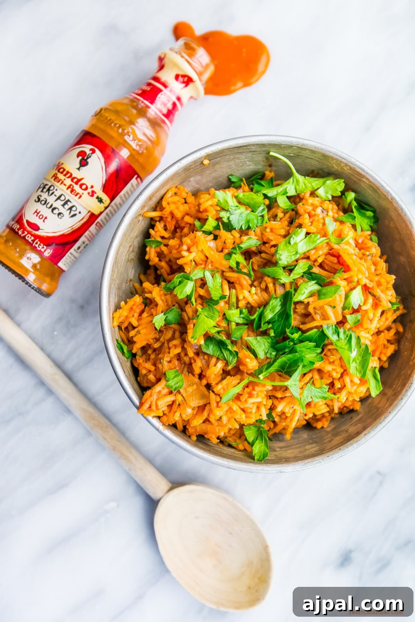 A delicious spicy Portuguese peri peri style rice dish, served with a bottle of the signature sauce and a spoon.