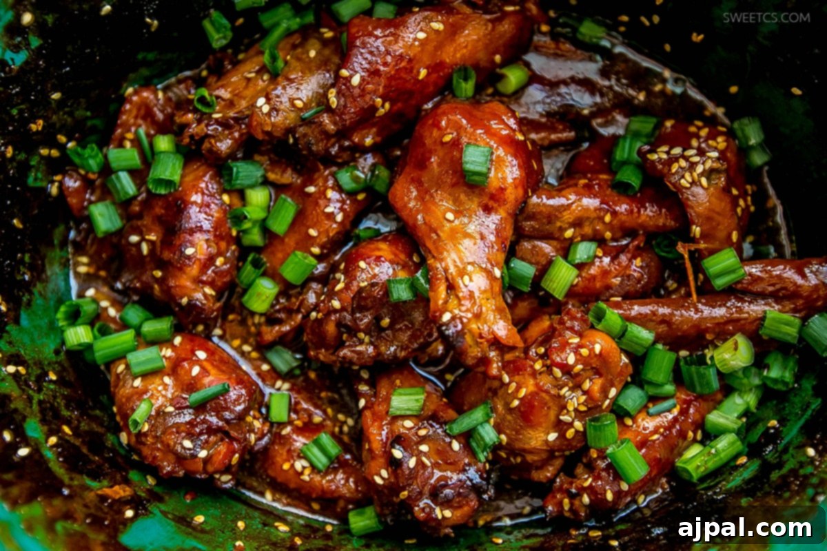 Sticky Honey Soy Slow Cooker Chicken Wings 4 Sticky Asian chicken wings presented in a vibrant green bowl, garnished with fresh herbs.
