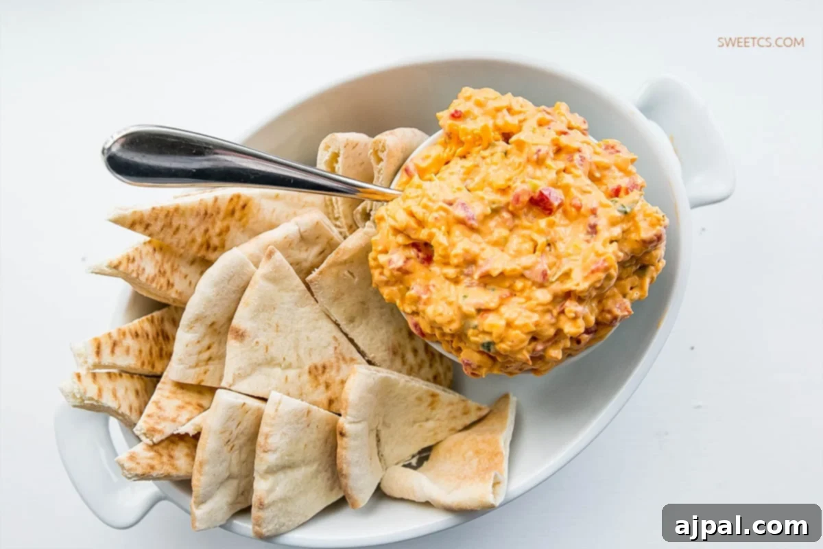 A bowl of the best homemade Pimiento Cheese Dip, garnished and ready to be enjoyed with a variety of dippers.