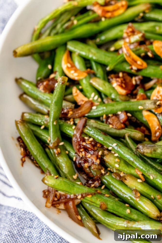 Chinese style green beans with sesame seeds in a white bowl.