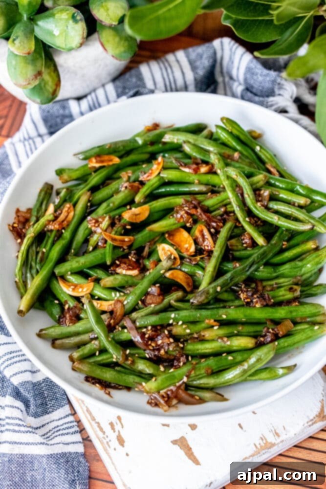 Garlic Chinese style green beans topped with sesame seeds in a white bowl.