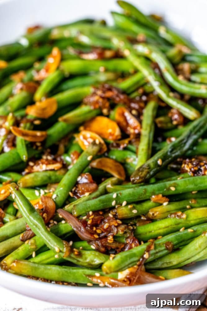 Chinese style green beans with sesame seeds in a white bowl.