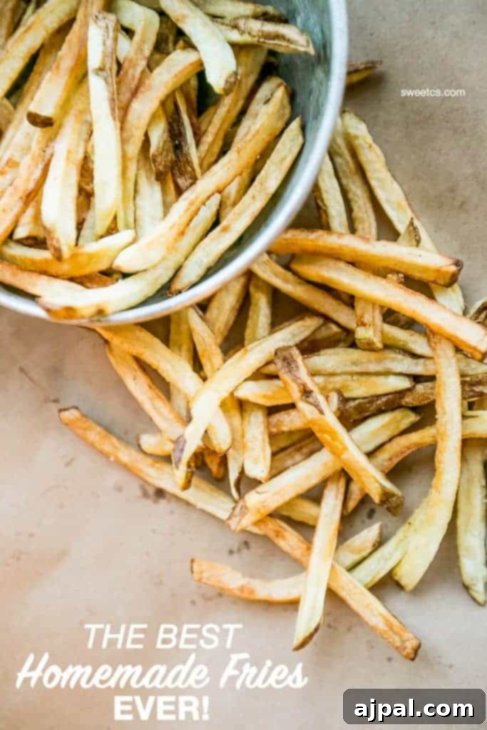 The Best Homemade Flash Fried French Fries 2 Crispy homemade french fries in a metal bowl, overflowing onto brown paper, showcasing their golden crunch.
