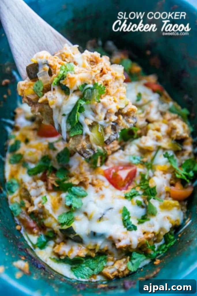 Easy Slow Cooker Chicken Taco Bowls 5 Appetizing chicken taco and vegetable mix in a slow cooker, adorned with a generous topping of melted cheese