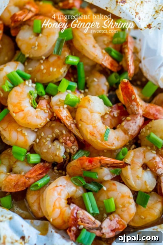 A baking sheet filled with perfectly cooked honey ginger baked shrimp, adorned with sesame seeds and freshly chopped green onions, showcasing a delicious and easy Asian-inspired meal.