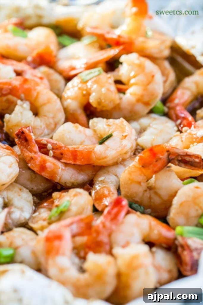 Succulent honey ginger baked shrimp arranged beautifully in a white serving dish, garnished with fresh green onions, ready to be served as an irresistible main dish or appetizer.