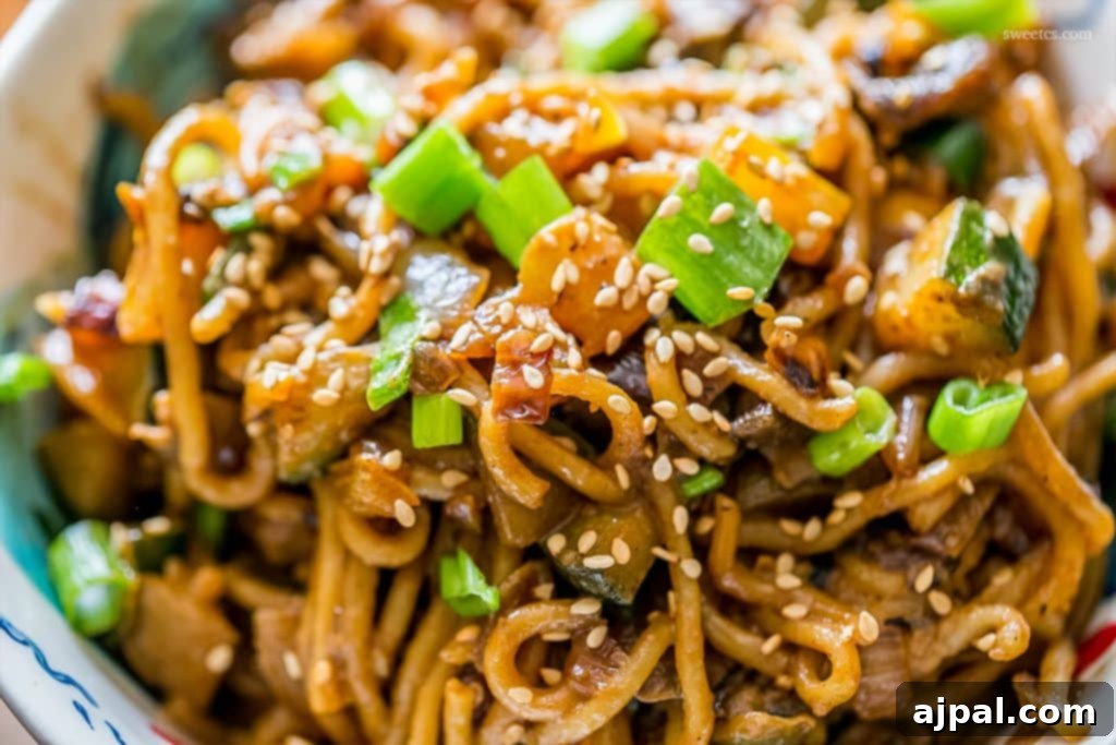 Velvety Tahini Noodles 4 A close-up of creamy vegan tahini noodles topped generously with sesame seeds and fresh green onions.