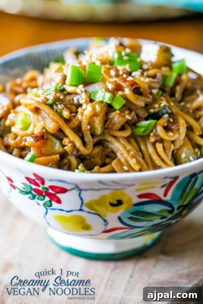 Velvety Tahini Noodles 5 A beautiful floral bowl piled high with creamy vegan tahini noodles, garnished with green onions and sesame seeds.