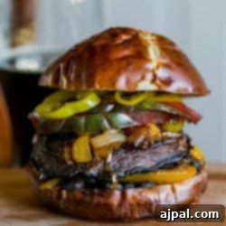 A spicy vegan portobello burger topped with mushrooms and peppers on a wooden cutting board.