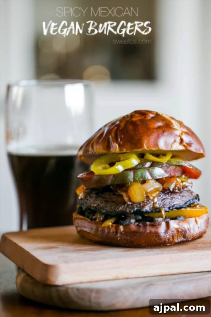 A beautifully assembled spicy vegan portobello burger with a Mexican twist, featuring fresh tomatoes, banana peppers, grilled onions, and bell peppers on a pretzel bun, ready to be enjoyed.