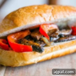 A vegan hoagie with mushrooms and peppers on a wooden board.