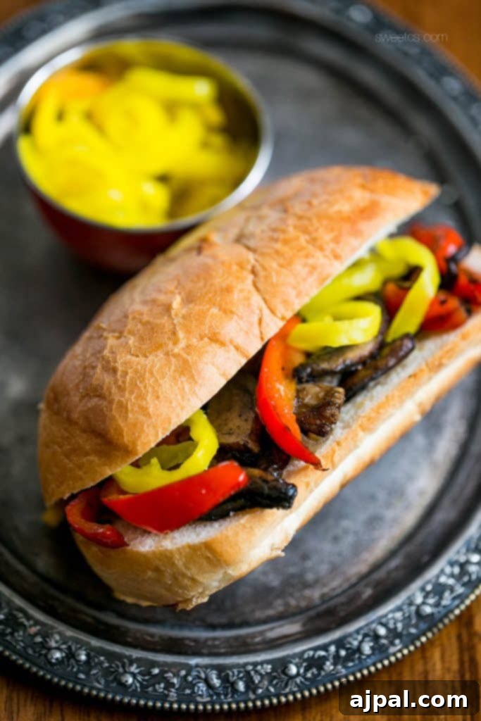 A gourmet vegan Philly sandwich with roasted bell peppers, mushrooms, and onions, artfully arranged on a plate.