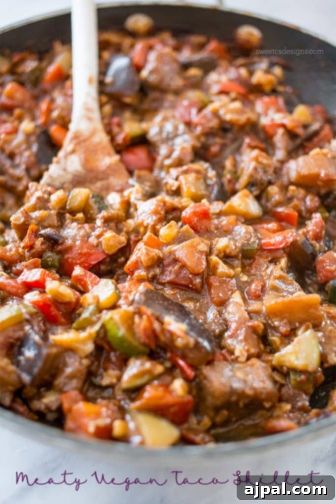 Kickin' Vegan Samosas 4 A savory vegan taco skillet mixture featuring tomatoes, lentils, zucchini, and sauce, presented with a wooden spoon.