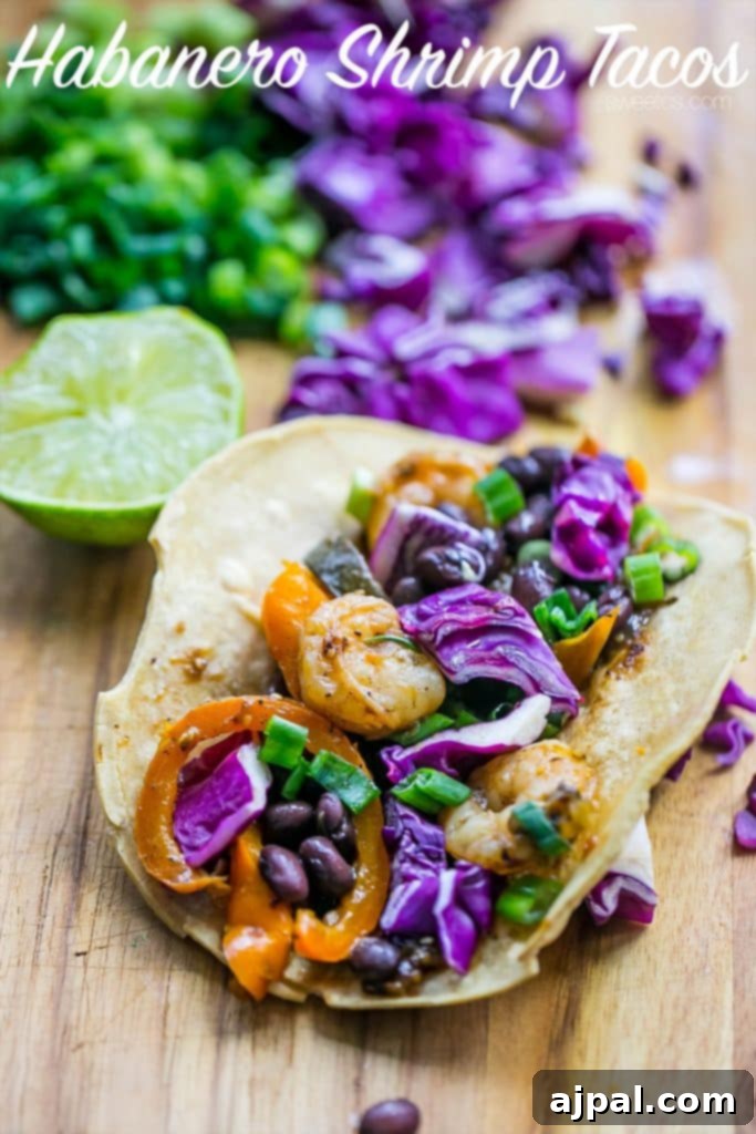 Spicy and delicious Habanero Shrimp Tacos arranged on a rustic wooden cutting board, ready to be enjoyed.
