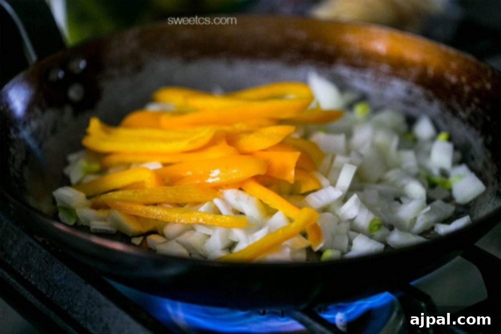 Zesty Old Bay Shrimp Fajita Tacos 4 A sizzling frying pan with onions and peppers, perfect for making fajitas or shrimp tacos.
