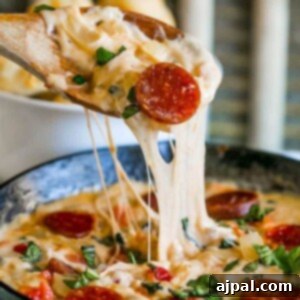 Cheesy spoon dipping into pepperoni dip.