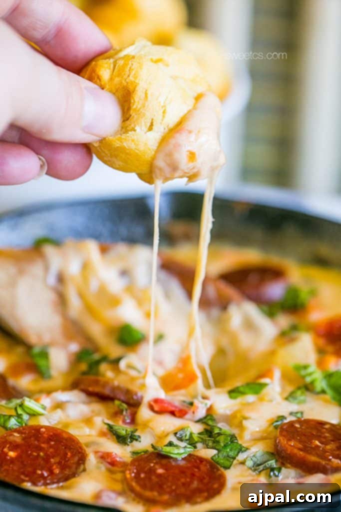 Picture of bread roll bring dipped into melted pizza cheese dip 