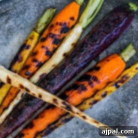 Golden Skillet Butter Carrots 6 Pan roasted butter carrots and parsnips with charred marks are artfully arranged on a gray surface, showcasing their vibrant, earthy hues.