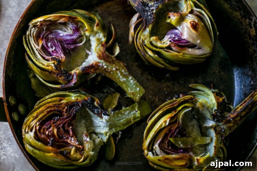 Close-up of a pan-seared artichoke half, beautifully charred and glistening with melted garlic butter and aromatic herbs.