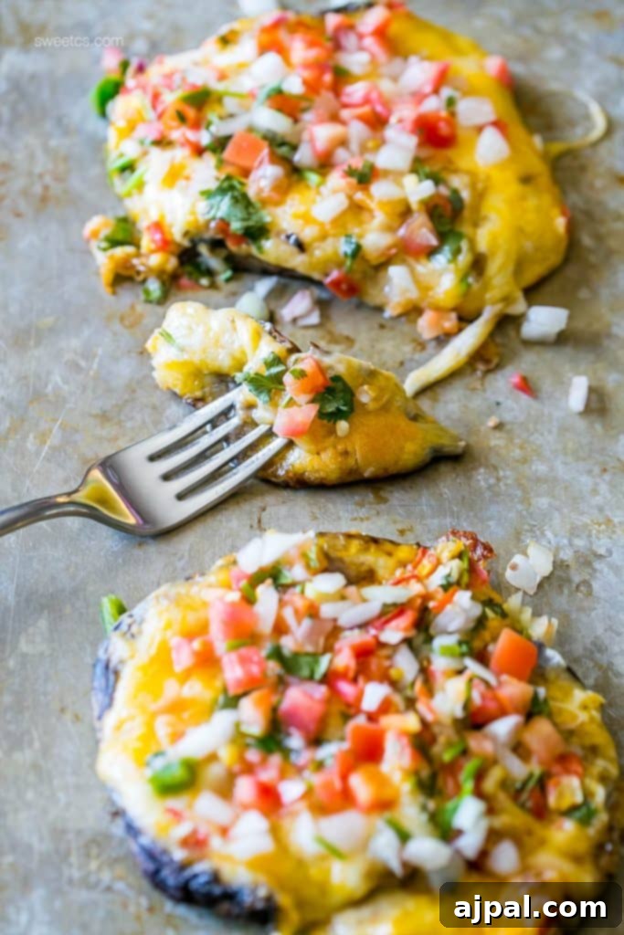 Fiesta Stuffed Mushrooms 5 Two generously stuffed portobello mushroom caps, topped with fresh salsa and a fork, on a baking sheet, reflecting a delicious low-carb taco alternative.