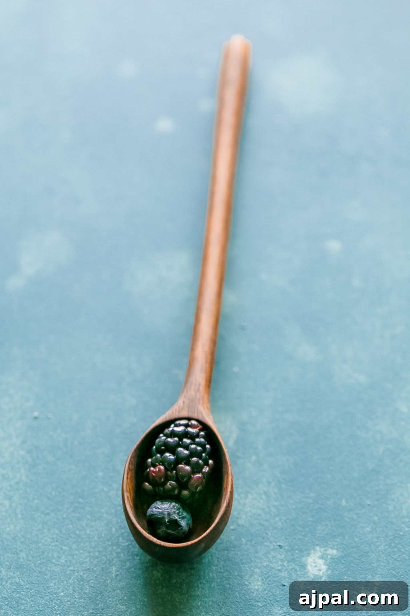 Berry Basil Garden Sparkler 9 A close-up of a rustic wooden spoon overflowing with fresh, vibrant mixed berries, highlighting their natural appeal.