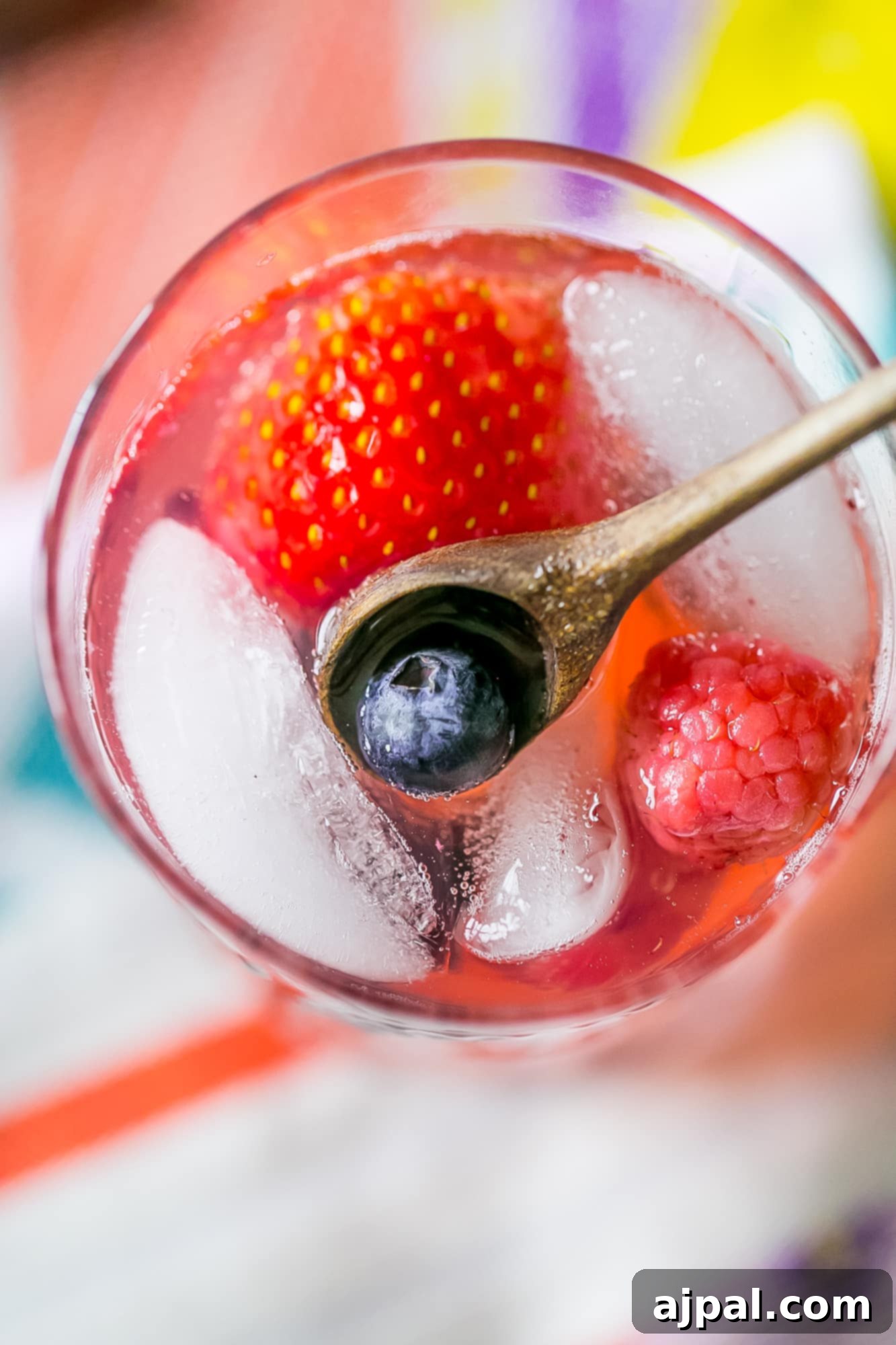 Berry Basil Garden Sparkler 3 Close-up of a glass of red lemonade with ice, berries, and basil, showcasing the vibrant colors and fresh ingredients.