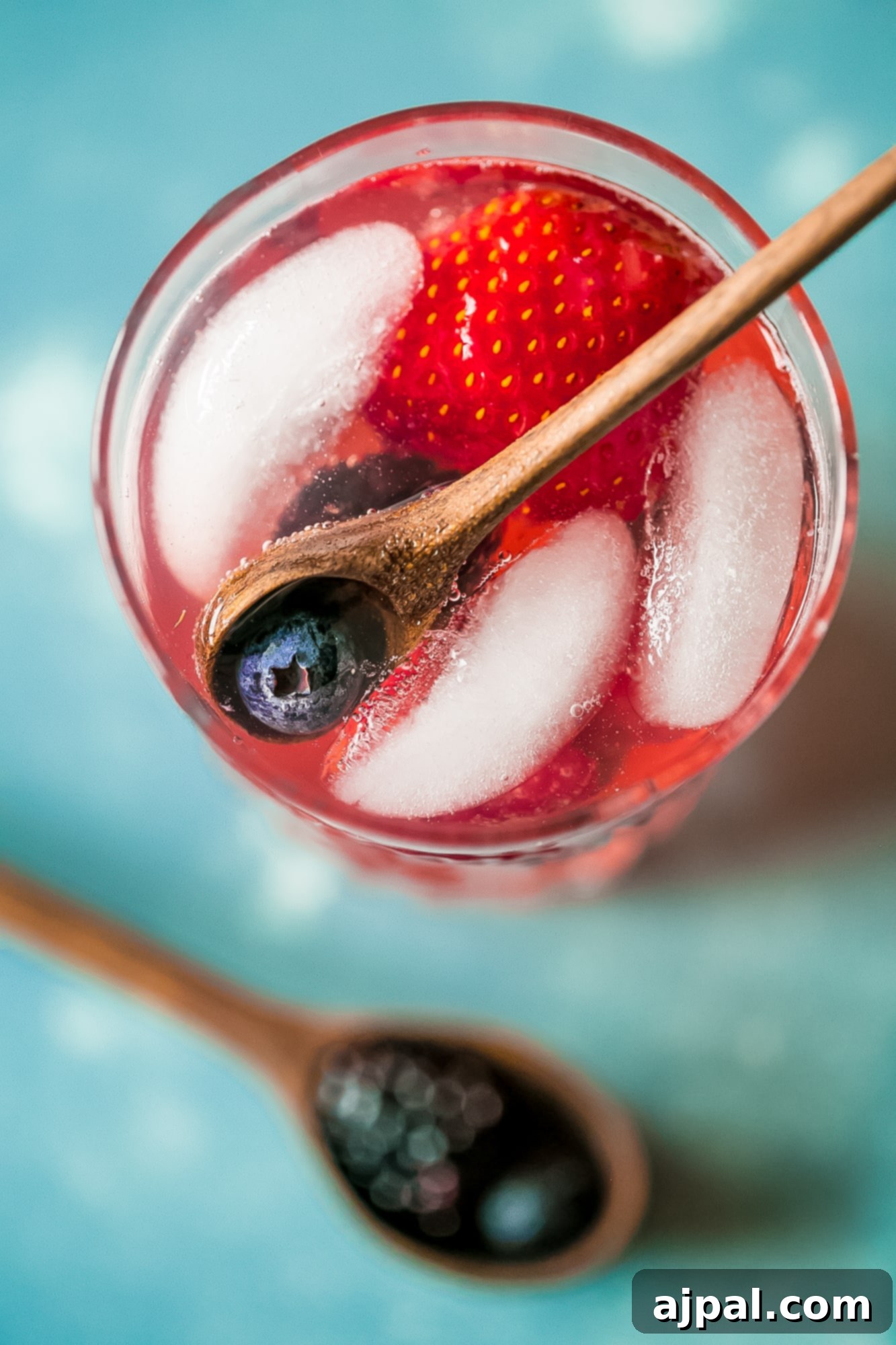 Berry Basil Garden Sparkler 5 A large glass pitcher filled with red lemonade, fresh strawberries, and blackberries, ready to be poured.