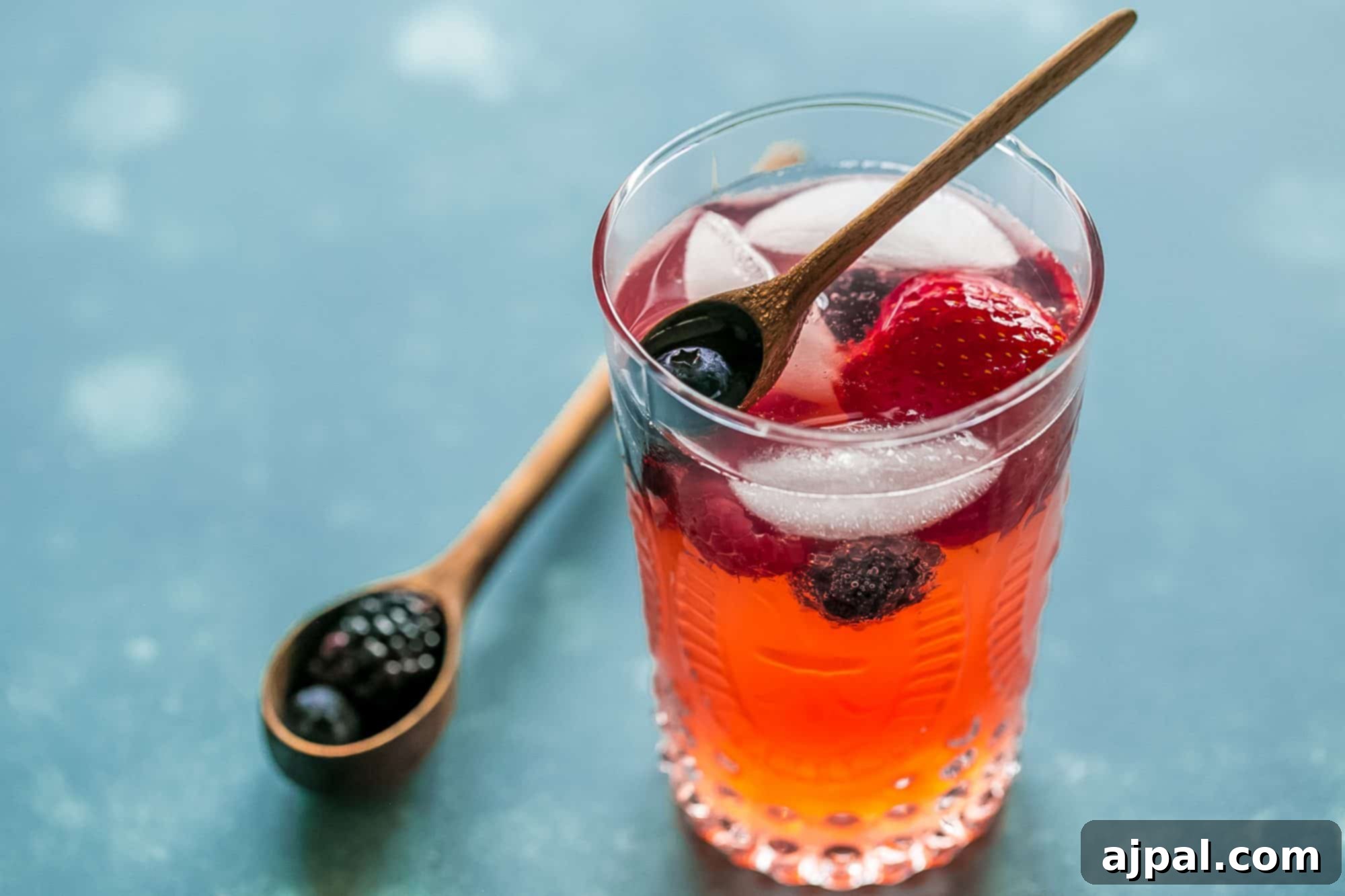 Berry Basil Garden Sparkler 7 A wide shot of a glass of red lemonade with ice and berries, positioned against a rustic wooden background, inviting a refreshing sip.