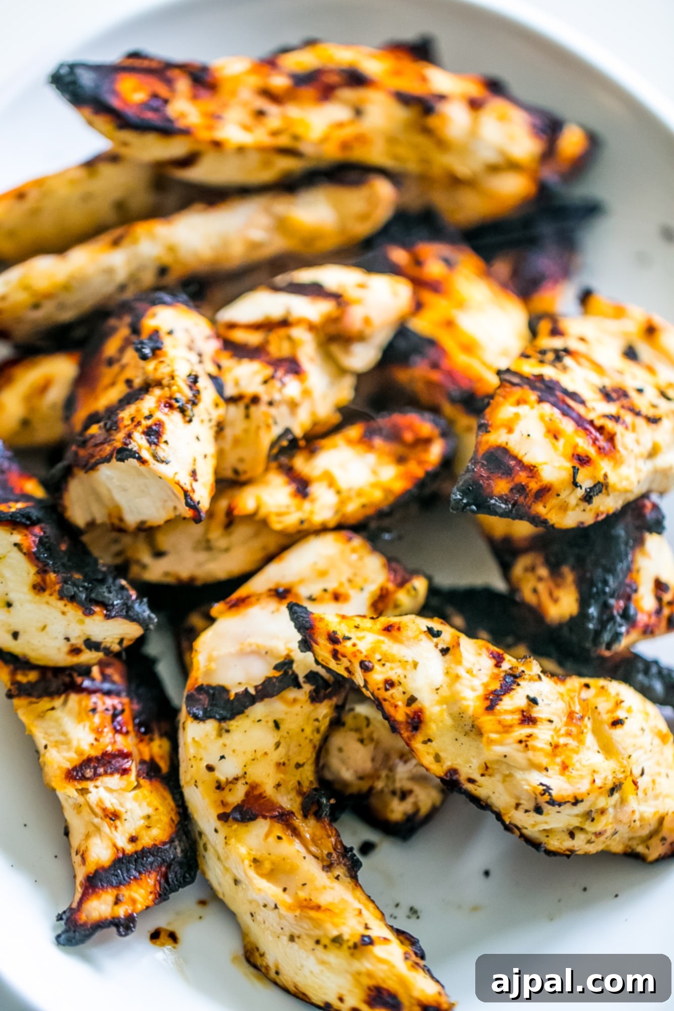 Grilled Chicken Perfection 5 A close-up of grilled chicken strips on a white plate, showcasing their perfect char and succulent appearance.