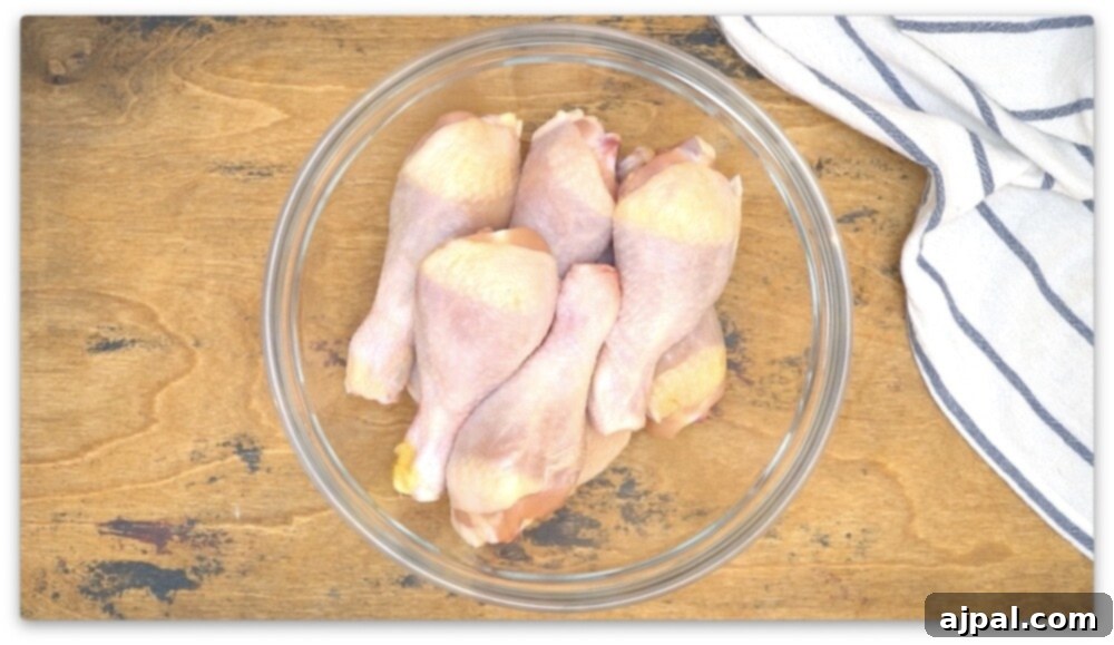 Chicken legs cooked in an air fryer, displayed in a glass bowl on a wooden table.