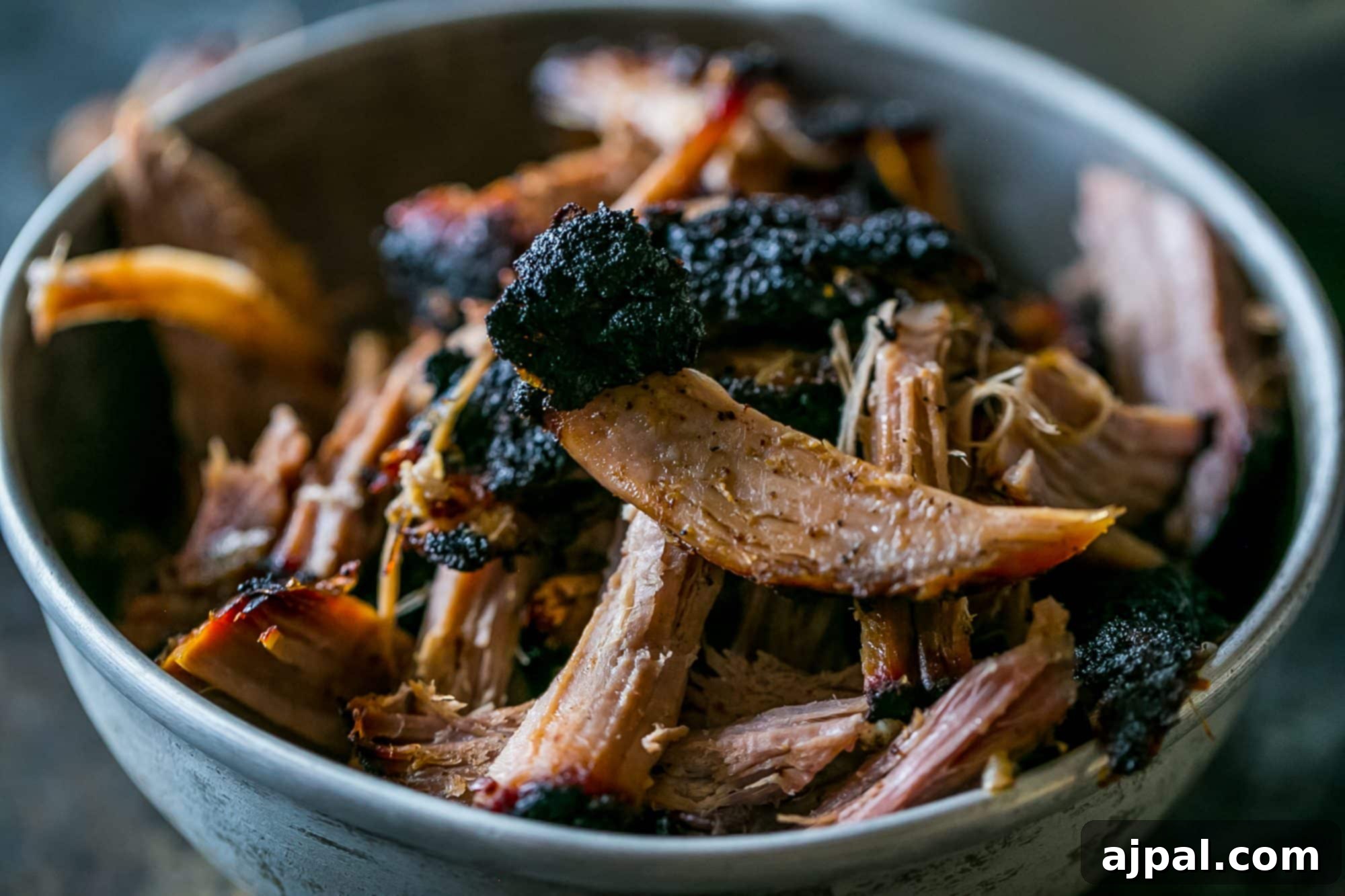 A generous serving of smoked pulled pork, glistening with juices, in a rustic bowl, ready to be enjoyed.