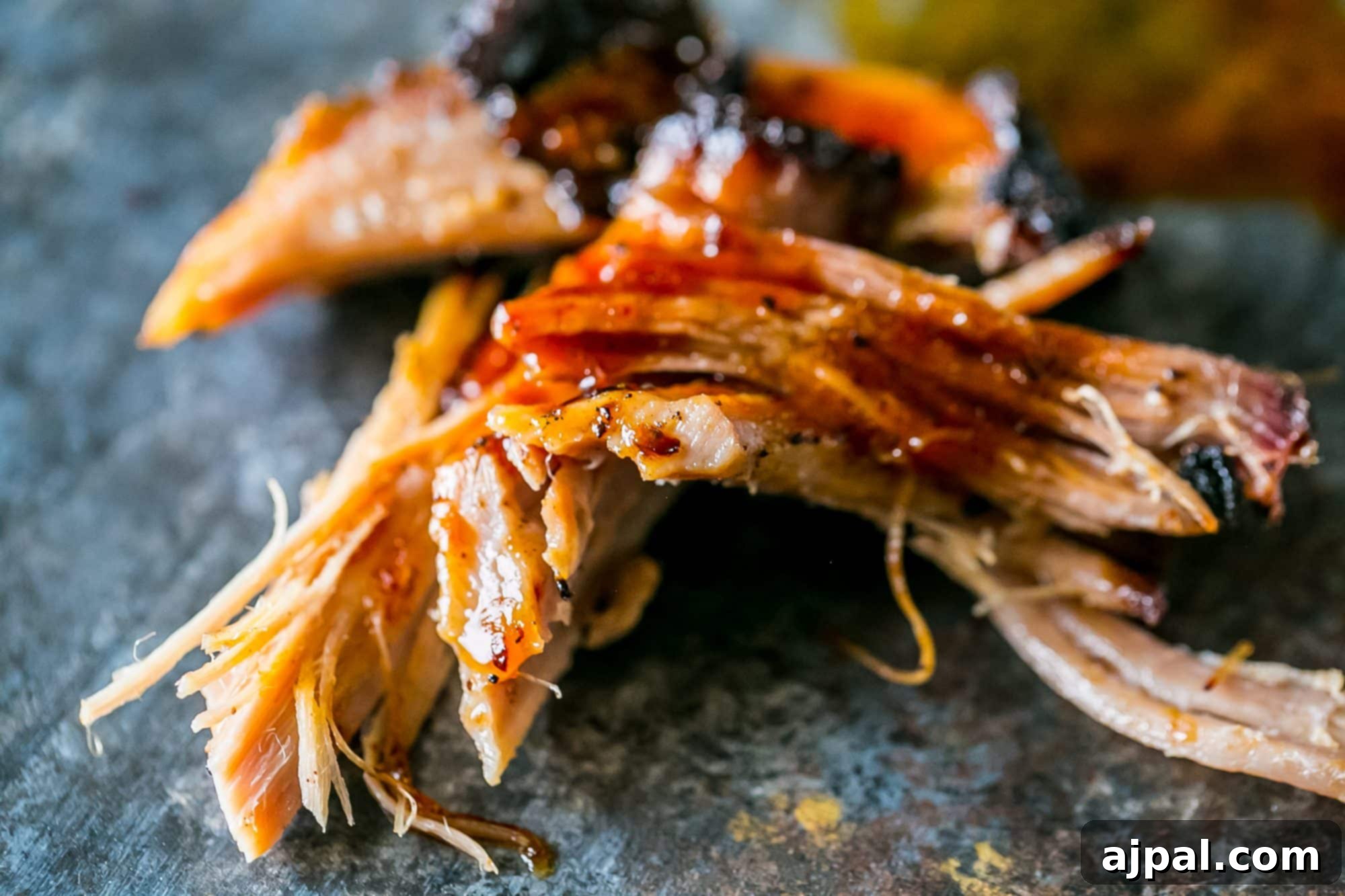 A close-up of tender, smoked pulled pork in a bowl, showcasing its rich texture and smoky bark.