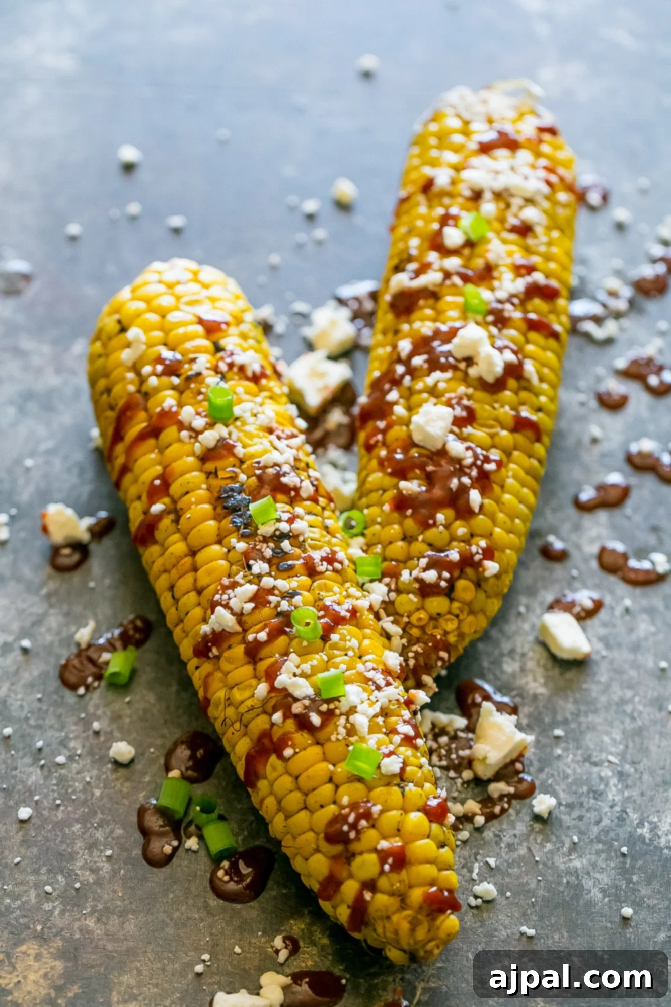 grilled corn smothered with sauce, cheese, and green onions
