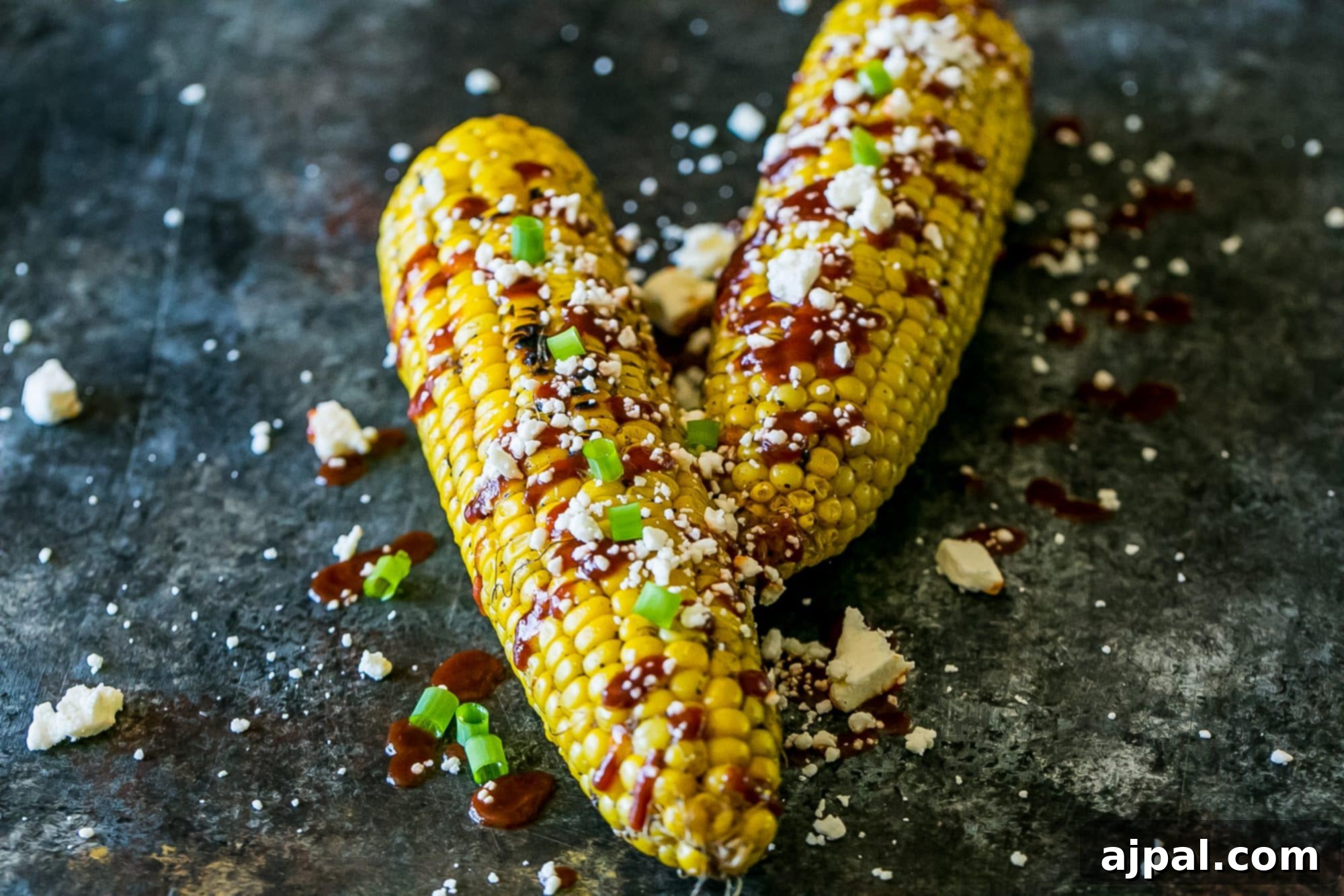 grilled corn smothered with sauce, cheese, and green onions