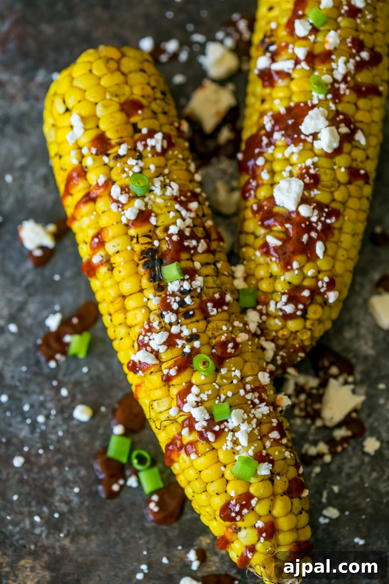 grilled corn smothered with sauce, cheese, and green onions