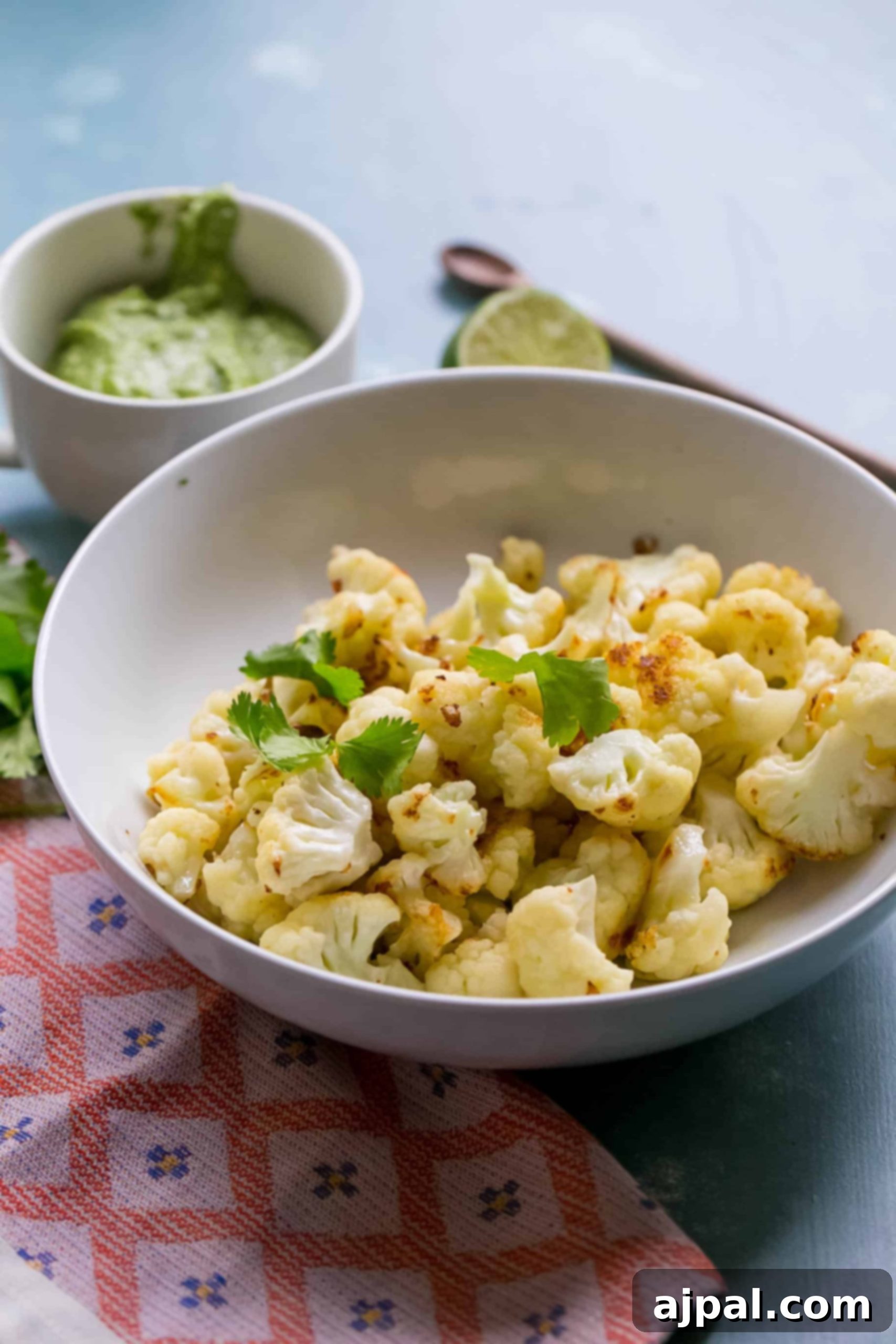 Golden Roasted Cauliflower with Zesty Cashew Pesto 2 A vibrant bowl of roasted cauliflower florets generously coated in a bright green cilantro cashew pesto, ready to be served.