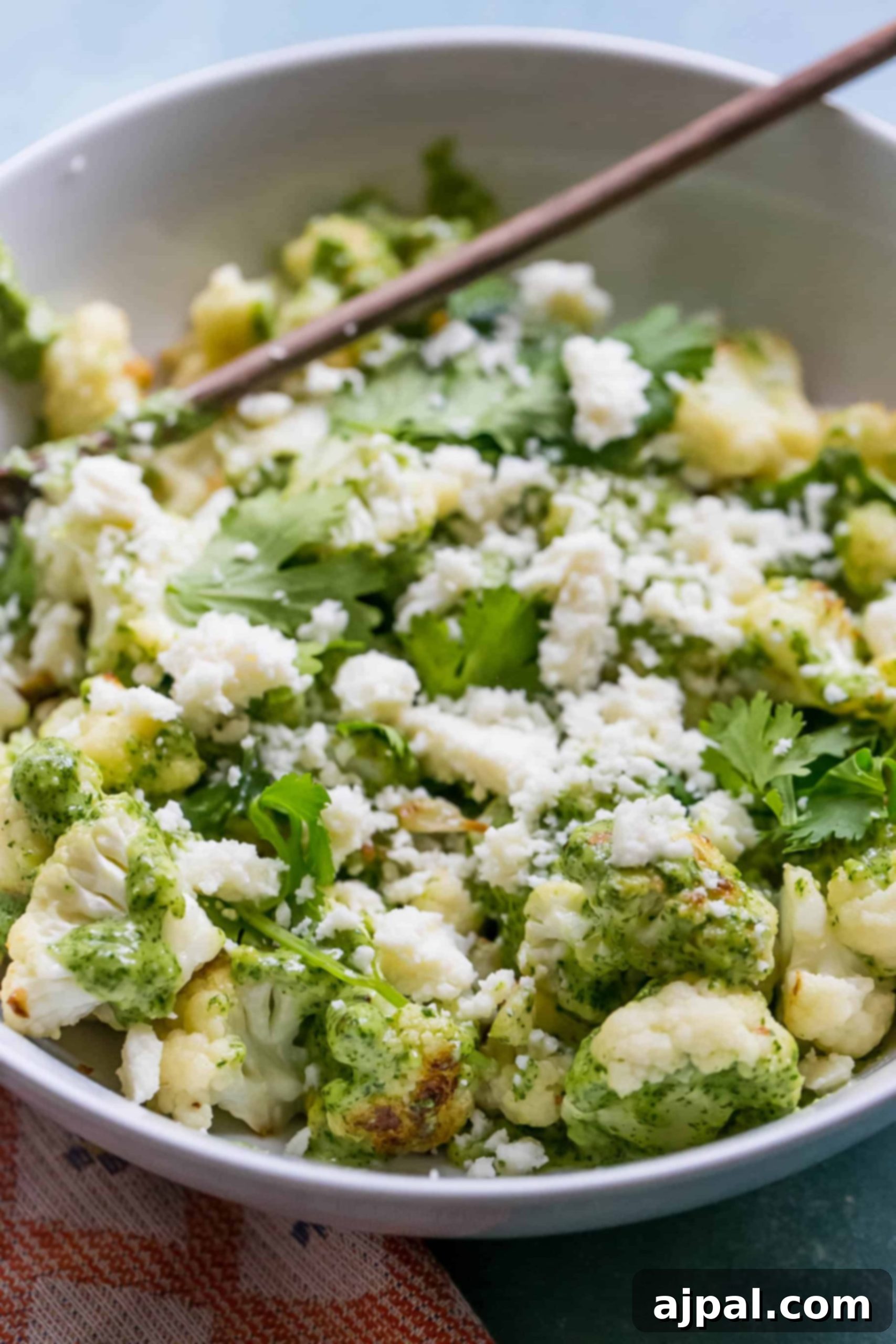 Roasted Cauliflower with Bright Cilantro Cashew Pesto 3 white bowl with cauliflower covered in pesto sauce and topped with crumbled white cheese