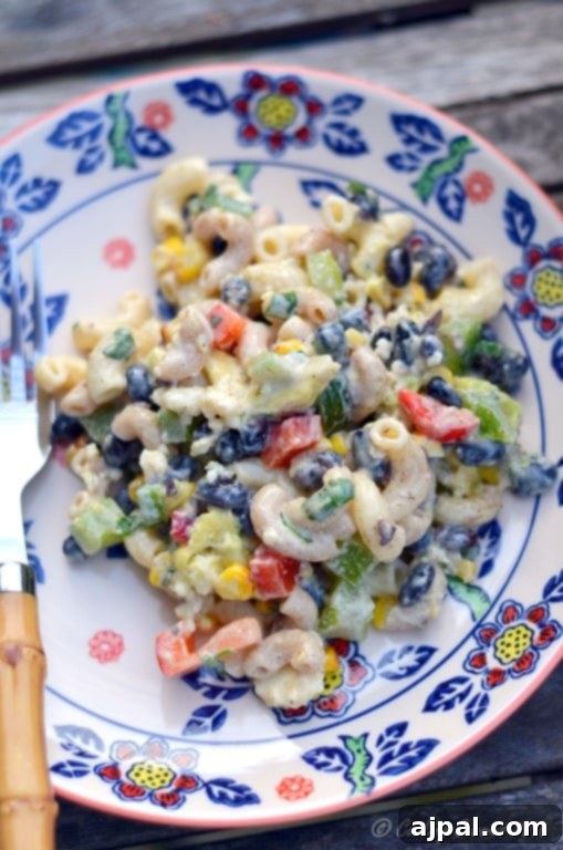 Black Bean & Pasta Salad with Cilantro-Lime Vinaigrette 2 A colorful bowl of cilantro lime black bean pasta salad featuring noodles, vibrant peppers, creamy dressing, sweet corn, and protein-rich black beans, perfectly mixed together.