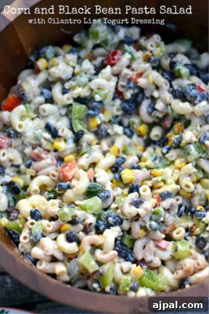Zesty Cilantro Lime Black Bean Pasta Salad 5 A serving of cilantro lime black bean pasta salad on a plate, featuring macaroni, corn, black beans, red bell peppers, and a creamy green dressing, garnished with fresh cilantro.