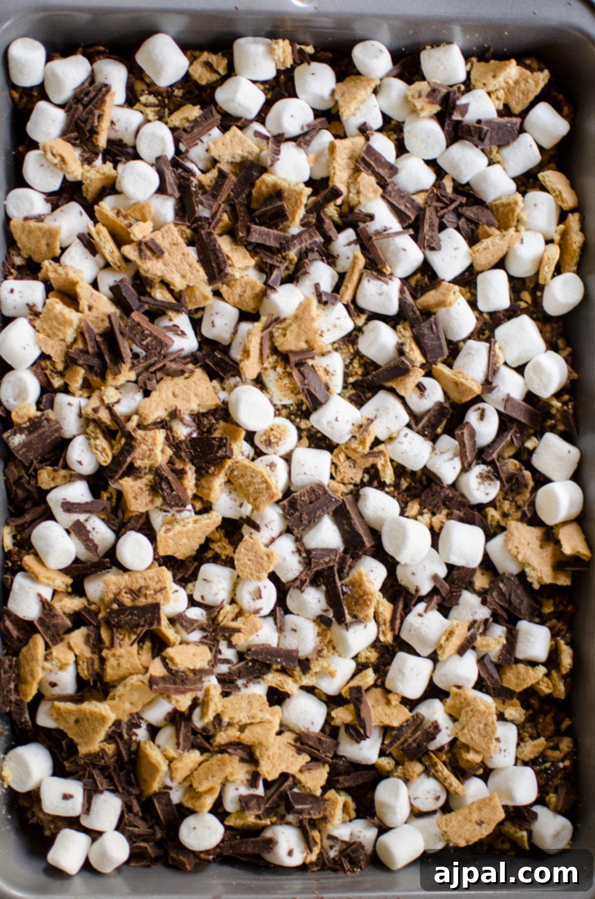 A pan full of s’mores made with graham crackers and rice krispie treats, with melted marshmallows and chocolate visible on top