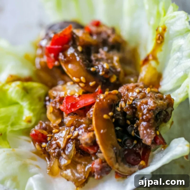 A sweet chili beef and mushroom lettuce wrap, served on a textured surface.