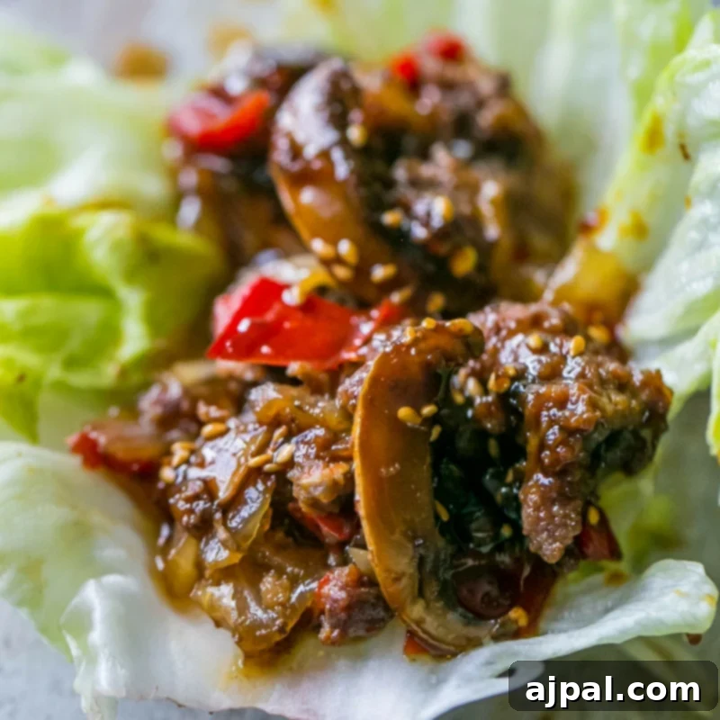 Close-up of a sweet chili beef and mushroom lettuce wrap, garnished with sesame seeds.