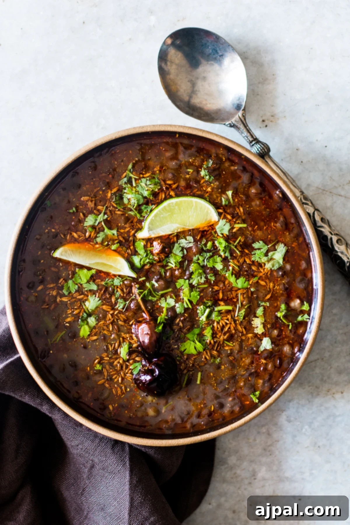 Indian Dal Soup 2 A steaming bowl of black lentil soup, garnished with fresh cilantro and a slice of lime, ready to be enjoyed.