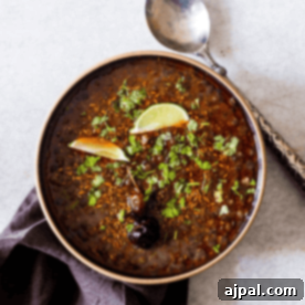 A bowl of Indian lentil soup with a spoon and lime.