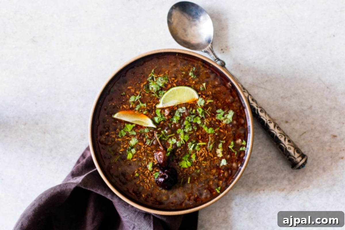 Indian Dal Soup 4 A beautifully composed image of black lentil soup, adorned with fresh cilantro and a vibrant lime, on a wooden surface.