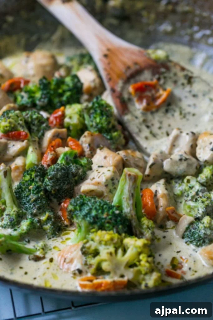 Creamy chicken broccoli alfredo in a bowl with a wooden spoon