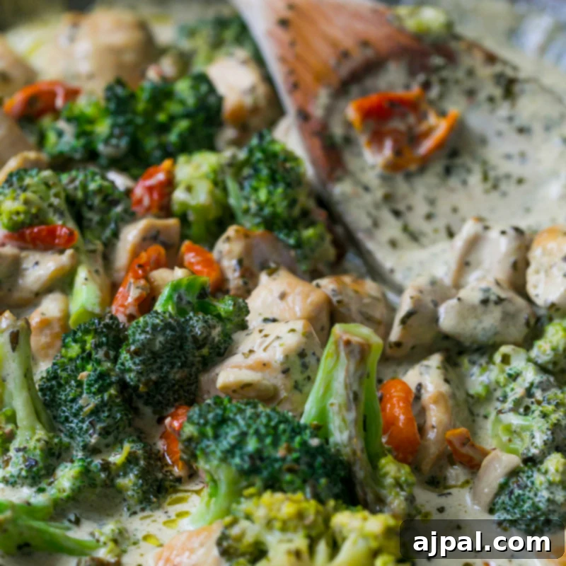 Creamy chicken broccoli alfredo in a bowl with a wooden spoon