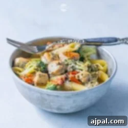 A creamy bowl of chicken and broccoli pasta with a fork.