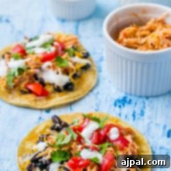 Two Mexican shredded chicken tacos on a blue background.